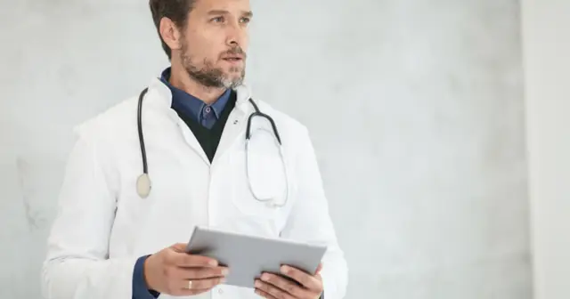 Doctor in a white coat holding a tablet