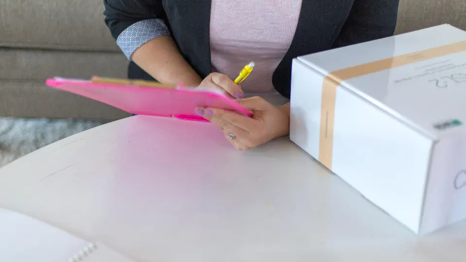 Person checking a delivery with a clipboard next to a box