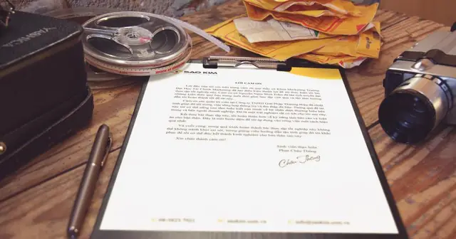 Printed document on a clipboard on a desk, with envelopes and a pen nearby