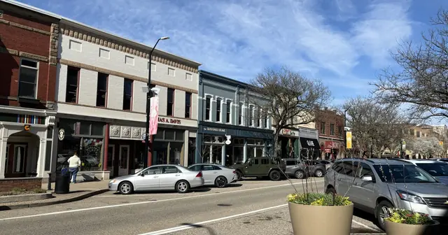 Small-town shopping street with storefronts and parked cars