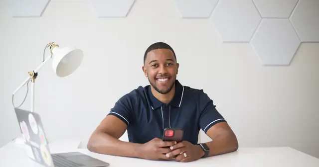 Smiling entrepreneur sitting at a desk with a laptop