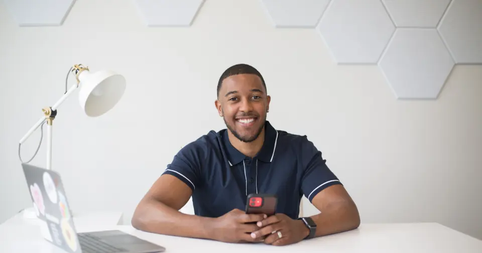 Smiling entrepreneur sitting at a desk with a laptop