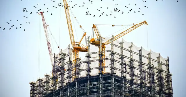 Building under construction with cranes against the sky