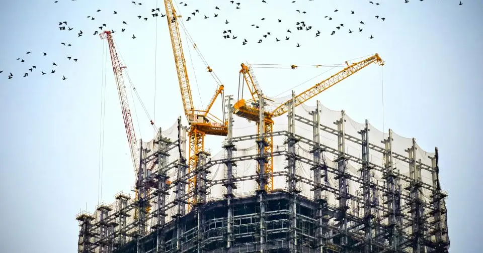 Building under construction with cranes against the sky