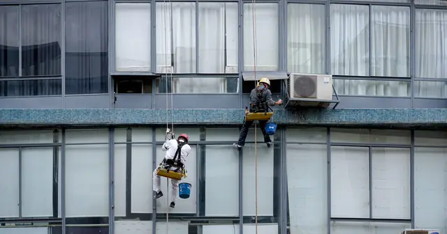 Two workers on ropes cleaning the glass facade of a building