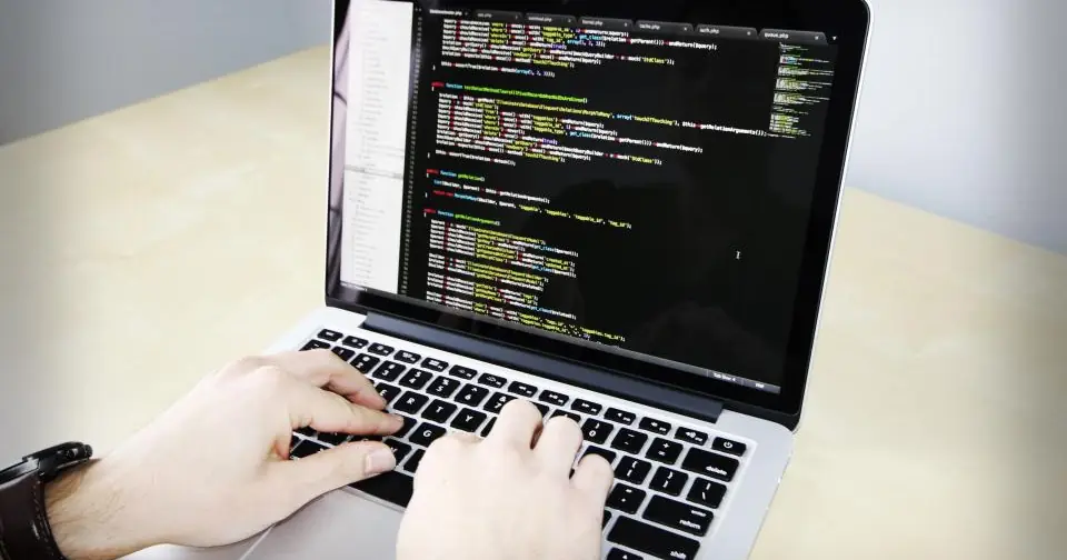 Hands typing code on a laptop